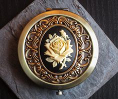 a gold and black clock with a white rose on it