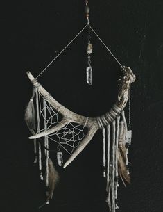 a dream catcher with feathers and beads hanging from it's sides on a black wall