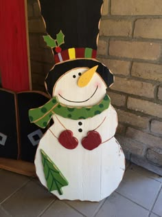 a snowman made out of wood sitting in front of a brick wall and door