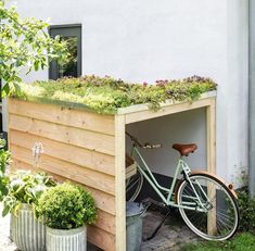 a bicycle is parked in front of a building with plants growing on the roof and side