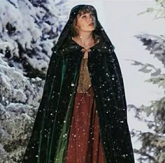 a woman wearing a black cloak and red dress in the snow