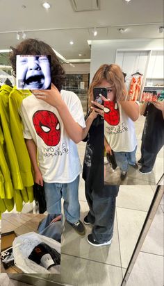 two children are standing in front of a mirror looking at their cell phones and taking pictures