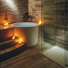 a bathroom with candles lit on the floor next to a bathtub and shower stall