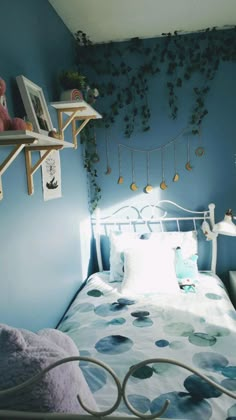 a bed in a bedroom with blue walls and hanging plants on the wall above it