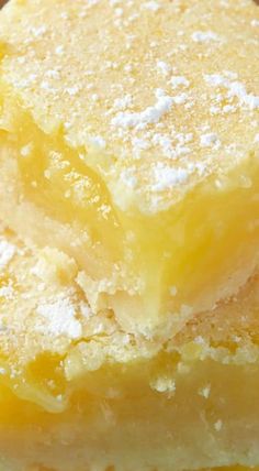 two pieces of lemon bars stacked on top of each other with powdered sugar on top