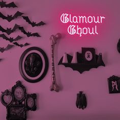 there is a neon sign that says glamour ghoul next to bats and clocks