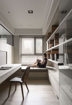 a woman is sitting on the window sill in her home office reading a book