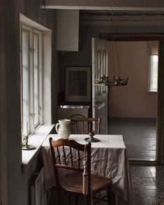 an empty dining room with a table and chairs next to the kitchen door, in front of a window