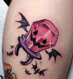 a pink diamond tattoo on the thigh with bats and stars around it's edges