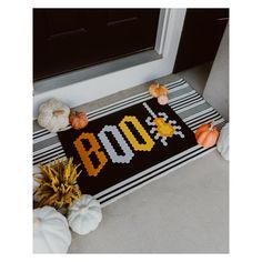 a door mat with the word boo spelled out on it next to pumpkins and gourds