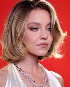 a woman with blonde hair and blue eyes wearing a white dress is looking at the camera