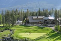 a golf course surrounded by pine trees and mountains