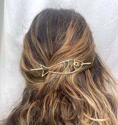 a woman wearing a gold fish hair clip