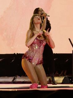 a woman is performing on stage with her hands in the air while holding a microphone