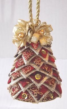 a christmas tree ornament hanging from a rope with bells and bows on it