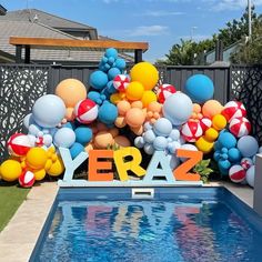 a pool decorated with balloons and letters that spell out the word year zero next to a swimming pool