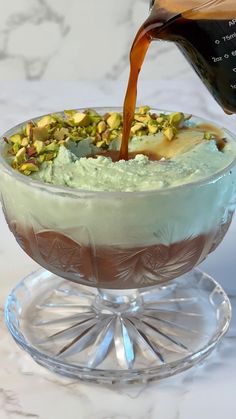 someone pouring something into a dessert in a glass bowl