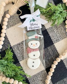 a snowman ornament sitting on top of a table next to some greenery