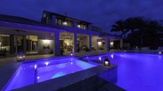 an outdoor pool lit up at night with blue lights on the side and in between