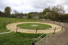 an empty baseball field in the middle of a grassy area with fenced in areas around it