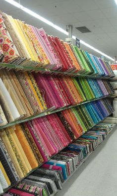 rows of colorful fabrics on display in a store