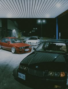 several cars are parked in a parking lot at night, with one red and the other black