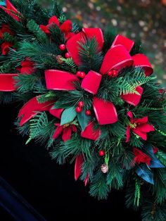 a christmas wreath with red bows and pine cones