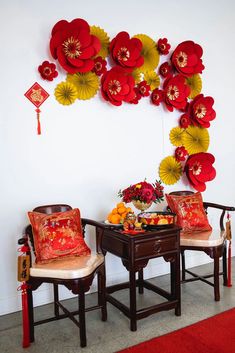 two chairs sitting next to each other in front of a wall with paper flowers on it