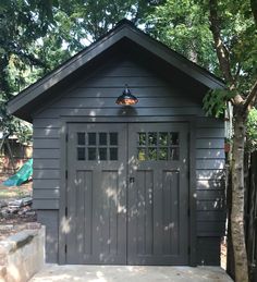 a gray shed sitting next to a tree