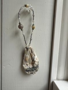 a necklace hanging on the side of a door with beaded beads and shells attached to it