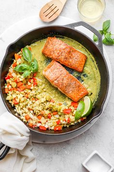 two salmons and rice in a skillet on a white table with utensils