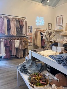 the inside of a clothing store with clothes and hats on display in front of it