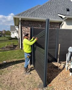 a man standing next to a fence in front of a house