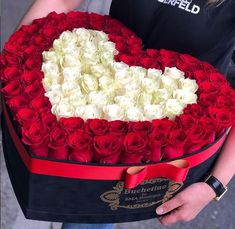 a woman holding a heart shaped box filled with roses