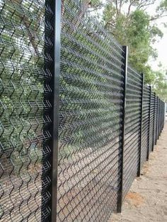 a black chain link fence on the side of a road with trees in the background