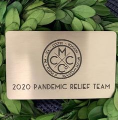 a metal plaque with the words pandemic relief team on it in front of some green leaves