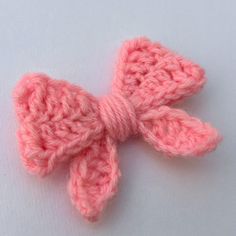 a pink crocheted bow on a white surface