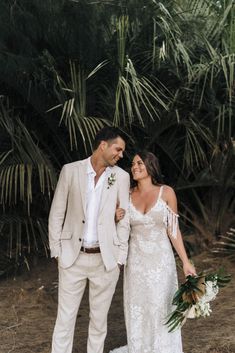 a bride and groom standing in front of palm trees