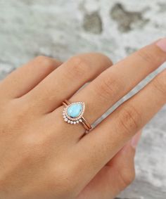 a woman's hand holding a ring with a blue stone in the middle and diamonds on it