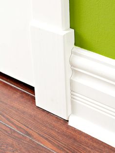 the corner of a room with a green wall and white trim on the door frame