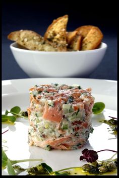 a white plate topped with food next to a bowl of bread