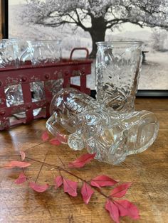 some glasses are sitting on a table next to a red wagon and pink leaves in the foreground