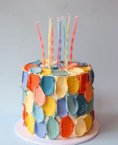 a multicolored birthday cake with candles on it