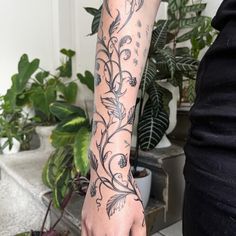 a woman's arm with flowers and leaves tattooed on the left side of her arm