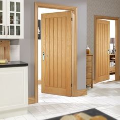 an open wooden door in a kitchen next to a white counter top and cupboards