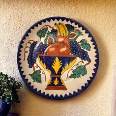 a blue and white plate with fruit painted on it next to a potted plant