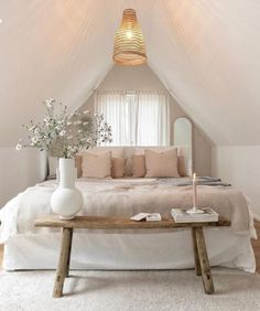 a white bed sitting under a window next to a table with flowers on top of it