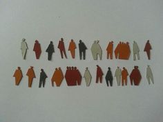 a group of paper cut people standing next to each other on top of a white surface