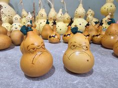 several pears with faces drawn on them sitting in front of other pears that are painted like angry men