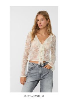 Semi-sheer lace blouse with a V-neck and long sleeves. Ruffle trims on the neckline and matching tie fastening.